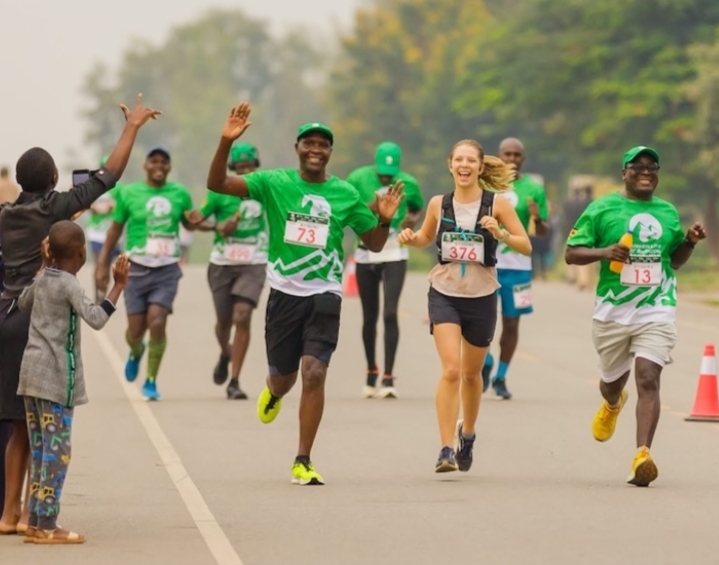 Madness in the Mountains: The Ultimate Mt. Rwenzori Marathon Guide & Where to Stay Runners happily waving at young children along the Mt. Rwenzori Marathon route.