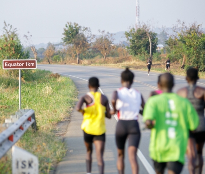 Madness in the Mountains: The Ultimate Mt. Rwenzori Marathon Guide & Where to Stay Marathon runners passing the 1km to Equator sign in Queen Elizabeth National Park.