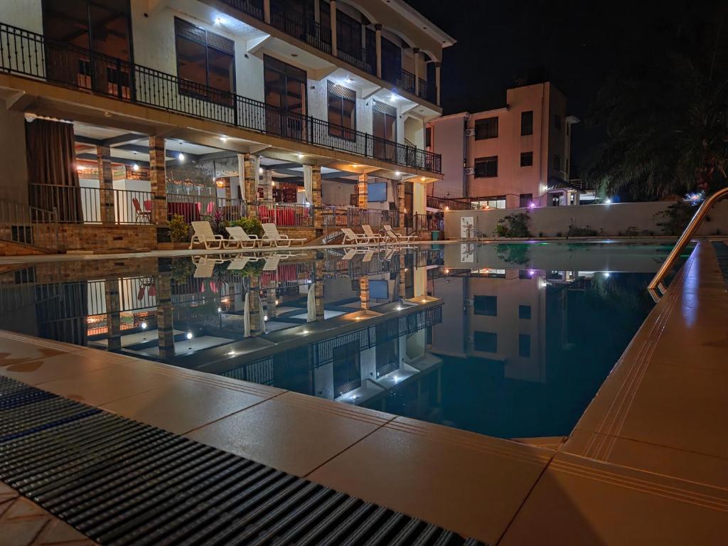 A night view of a luxurious swimming pool reflecting a modern multi-story hotel building at Mountain Inn Hotel in Maluku, Mbale, Uganda.