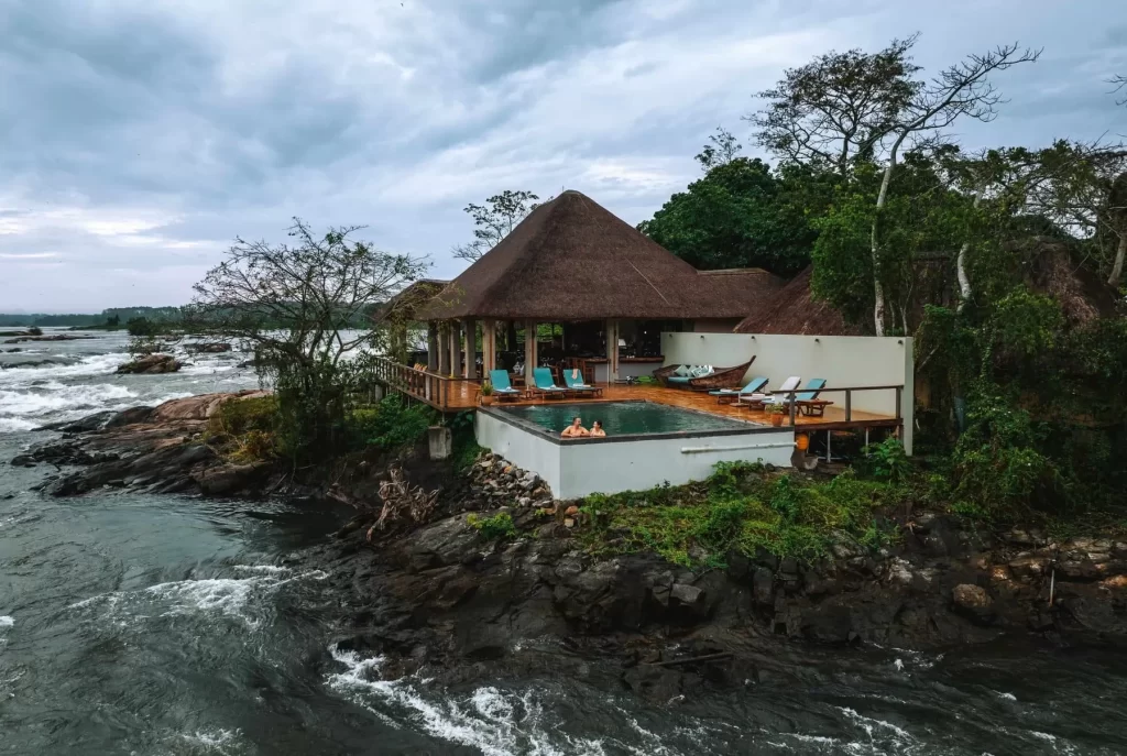 Lemala Wild Waters Lodge Jinja: The Ultimate Private Island Retreat. Wide-angle view of Lemala Wild Waters Lodge main pavilion and infinity pool, perched on a rock peninsula surrounded by the white-water rapids of the Victoria Nile.