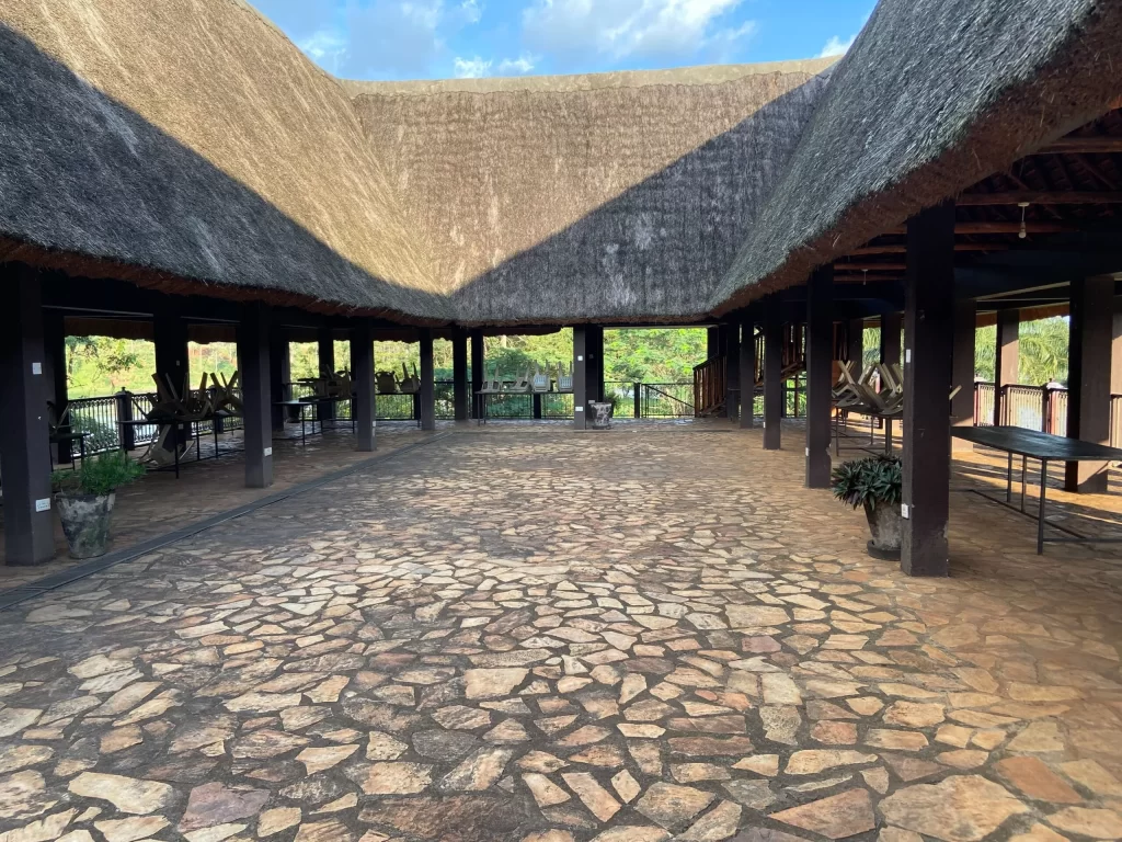 The expansive open-air lounge at The Nile River Bend Resort in Jinja, featuring a large thatched roof, natural stone flooring, and views of the surrounding greenery and Nile River.