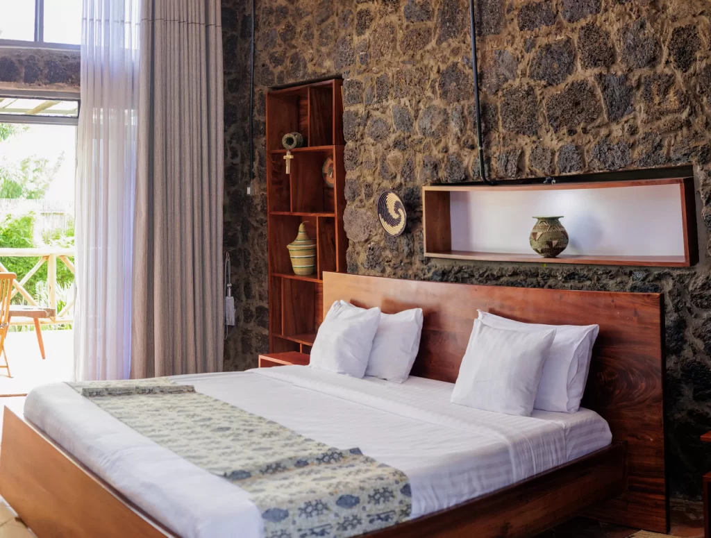 Imbogo Diners and Lounge luxury executive suite featuring crisp white linen on a king bed against a handcrafted volcanic stone wall