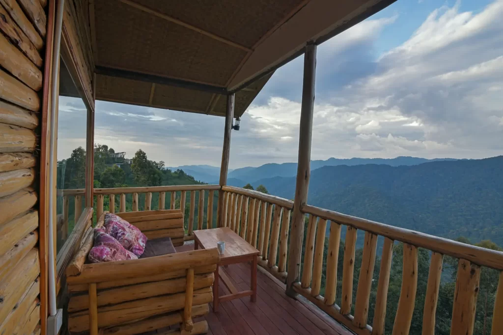 Bwindi Orugano Lodge private timber balcony with wooden lounge seating and a coffee table overlooking the rolling green hills of the forest