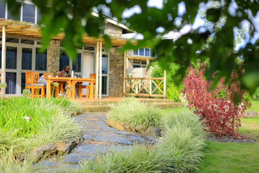 Imbogo Diners and Lounge outdoor dining veranda and main stone pavilion surrounded by a landscaped garden and lawn in Kisoro Uganda