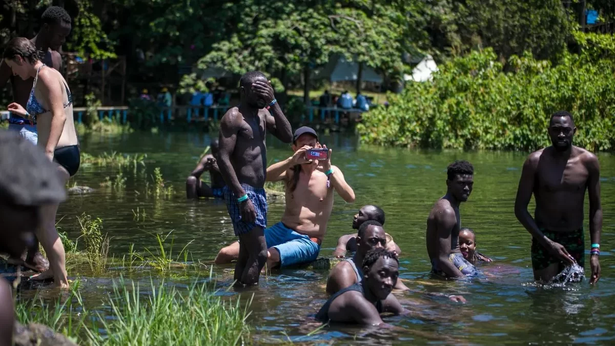 Nyege Nyege 2026 Guide A group of people relaxing and swimming in a river surrounded by trees in Jinja.