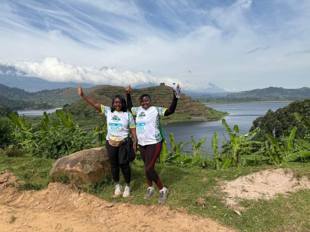 Marathon participants in official kits posing on a scenic highland ridge route with Lake Mutanda in the background.