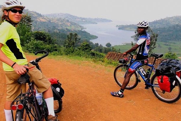 Cyclists pausing with their bicycles on a red dirt overlook path during a cycling route on a Jinja Uganda itinerary