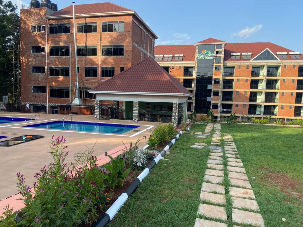 Exterior view of Mountain Inn Resort Jinja in Njeru Bujjowali showing the main brick accommodation buildings swimming pool and green lawns