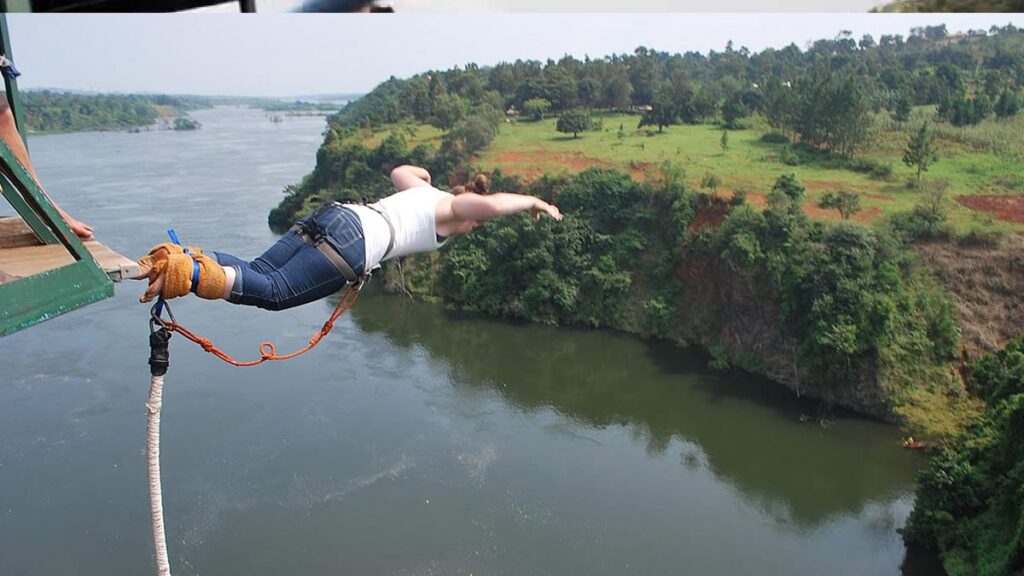 Bungee Jumping in Jinja: The Ultimate Guide to Uganda’s Adventure Capital A woman diving headfirst in a swan dive position during a bungee jumping in Jinja session, secured by a traditional ankle tie over the River Nile with lush green riverbanks in the background.