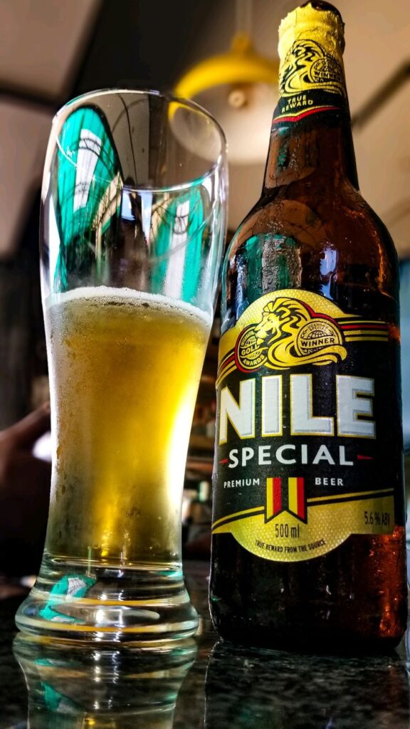 A cold 500ml bottle of Nile Special Premium Beer sitting next to a freshly poured, chilled glass of lager on a counter at Nyege Nyege festival in Jinja Uganda.
