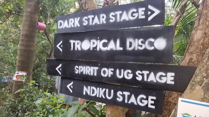 Black wooden directional signboards with white stenciled lettering pointing toward Dark Star Stage, Tropical Disco, Spirit of UG Stage, and Ndiku Stage at Nyege Nyege festival in Jinja Uganda.